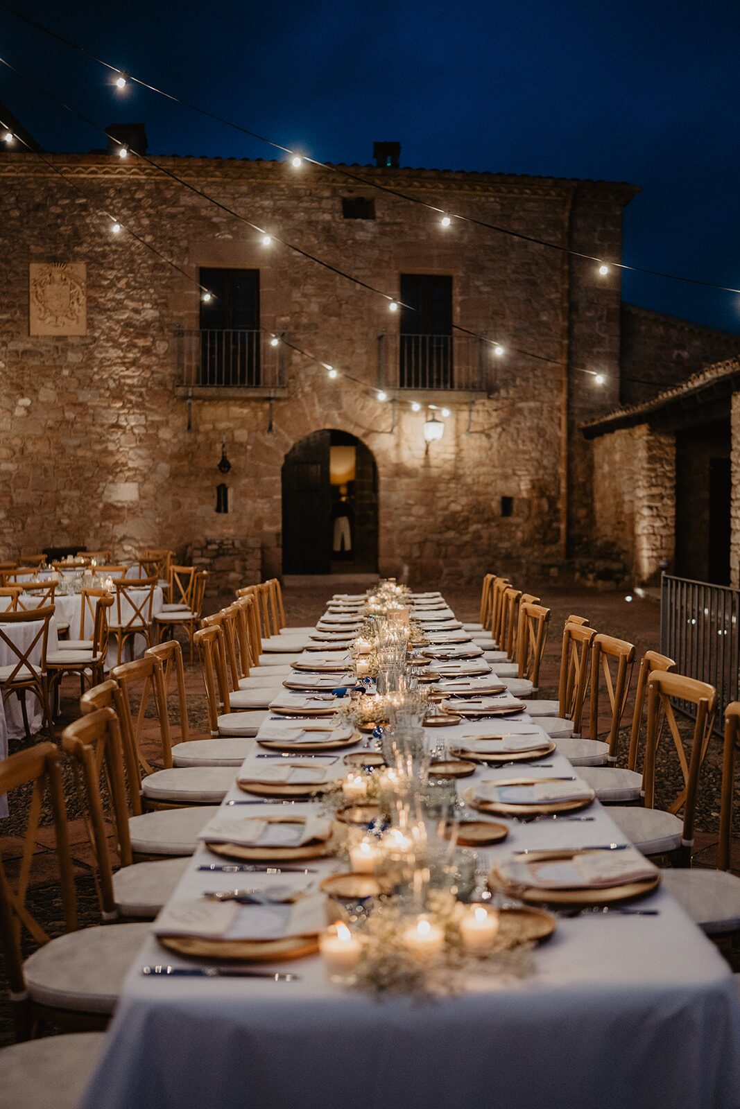 Mesa de boda iluminada con velas en un espacio histórico catalán diseñada por The Eve
