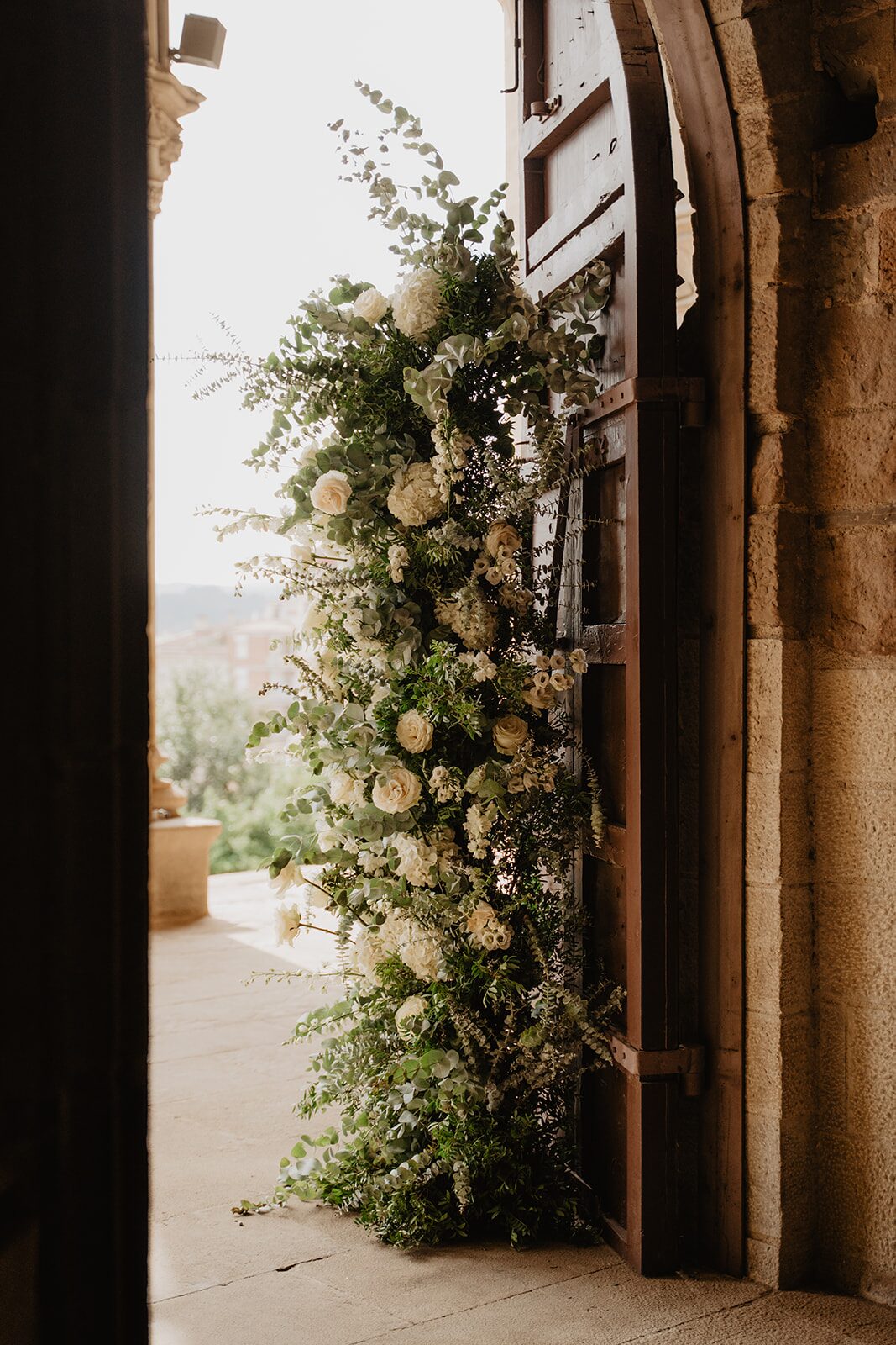 Decoración floral de rosas blancas y eucalipto en la puerta de una iglesia de Barcelona