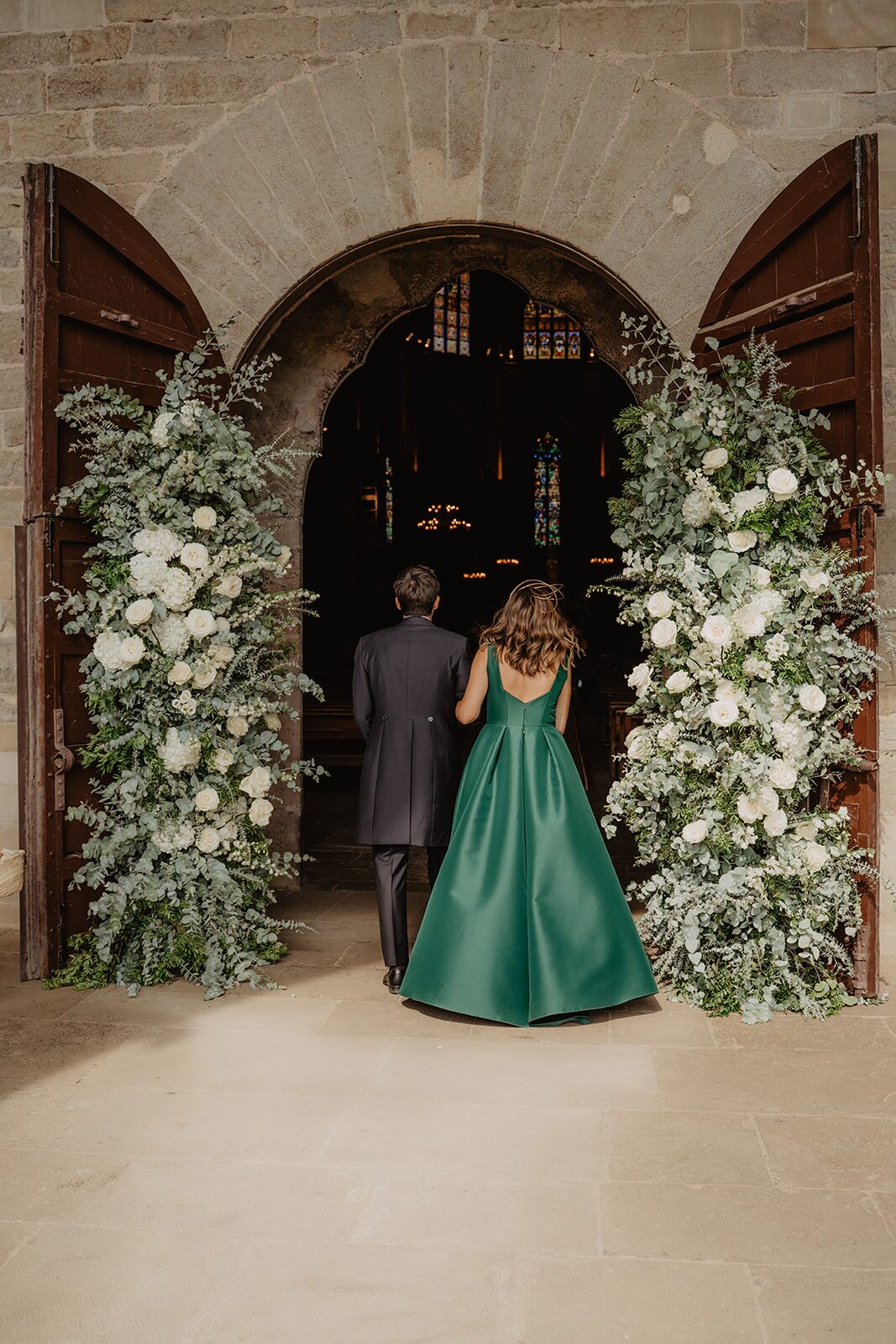 Invitada de boda con vestido verde entrando en una iglesia gótica de Cataluña