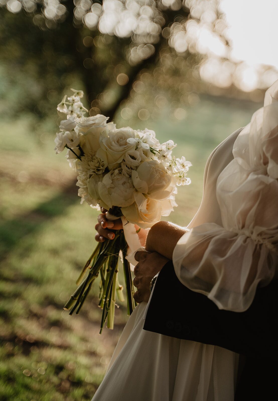 Ramo de novia de rosas blancas y peonías iluminado por el atardecer