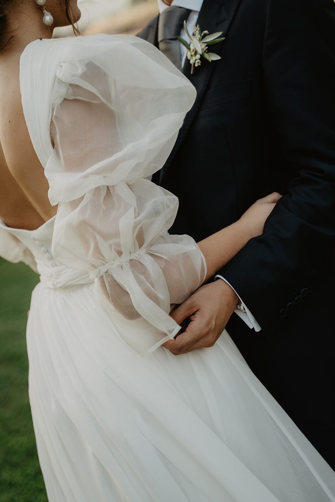 Detalle de una manga de organza y del vestido de novia