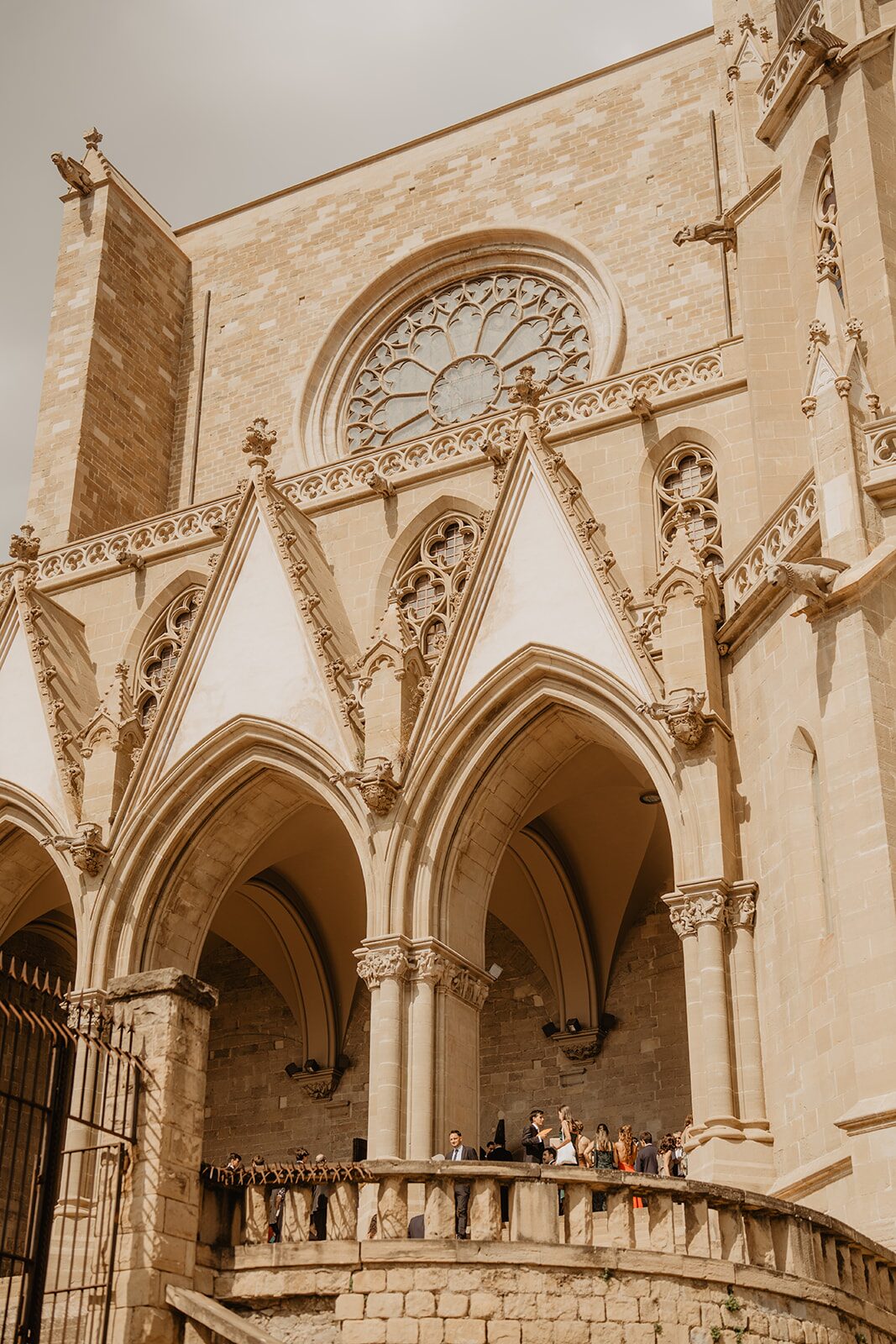Iglesia gótica en Cataluña con invitados de boda reunidos en la terraza